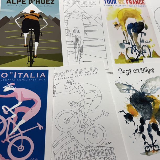 Collection of cycling-themed posters laid out on a table, featuring stylized riders and race titles like Tour de France and Italia.